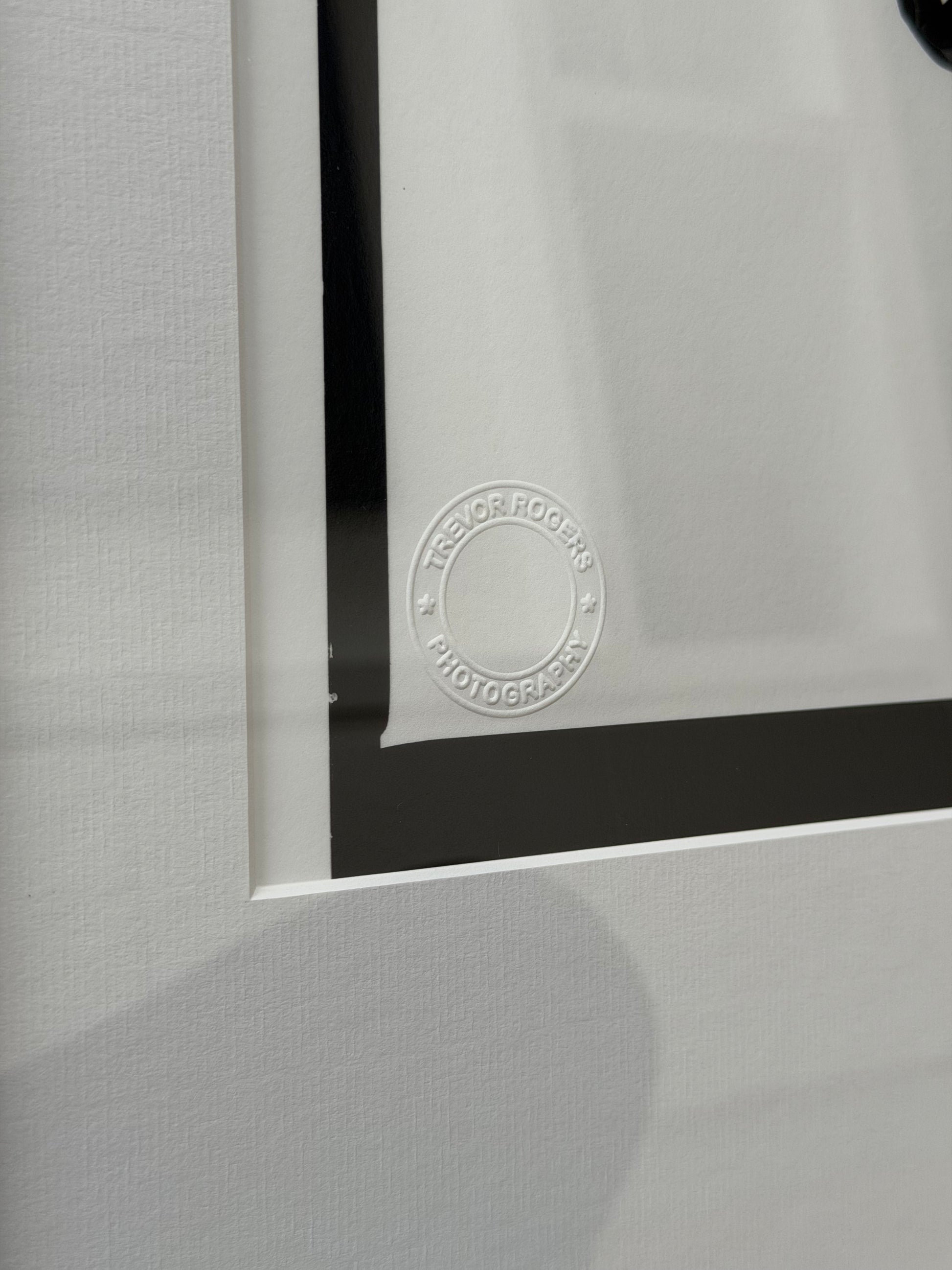 Close-up of a framed photograph with a visible signature on a gray textured background